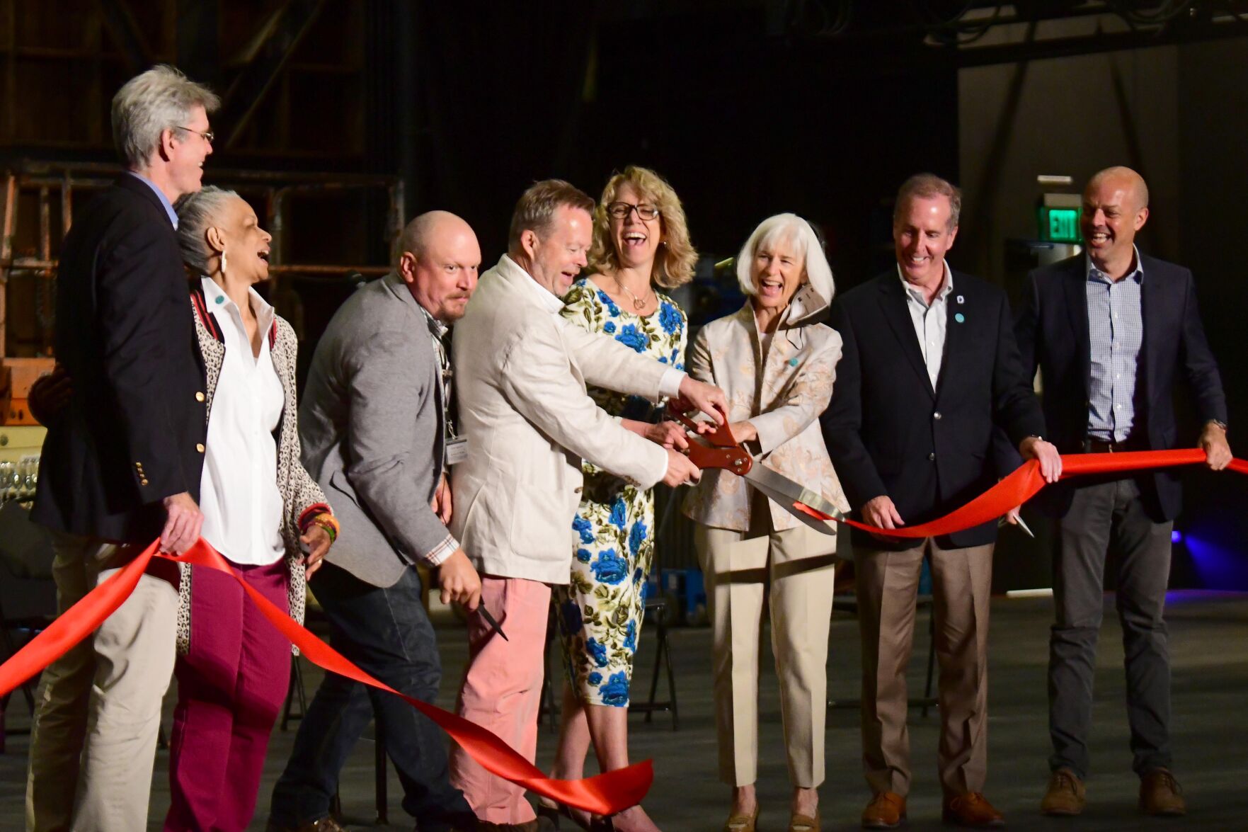 People on stage cut a ribbon